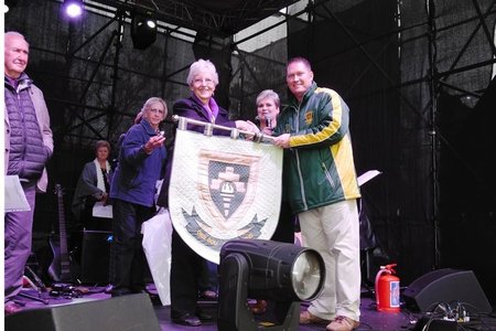 Olga Swanepoel oorhandig die skoolwapen van Bekker Landbou HoÃ«rskool, wat sy spesiaal gekwilt het, aan die skoolhoof tydens die skool se 80-jarige feesvieringe